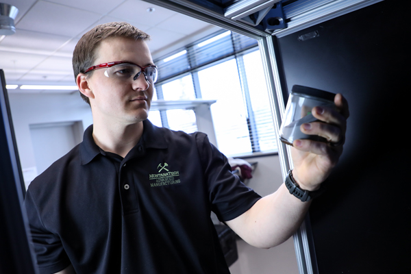 Student wearing safety glasses holding a jar in a lab