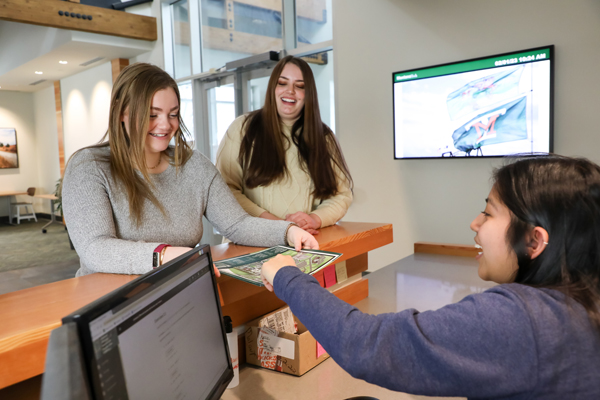 Two female students being assisted at a help desk