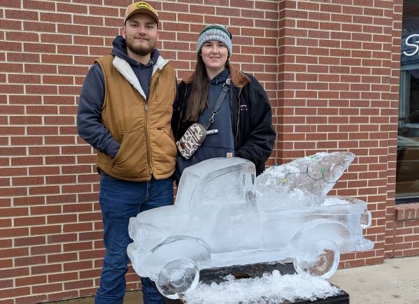 Ethan Heggem and Aubrey Teller pose with their ice carving of a vintage truck and Christmas tree