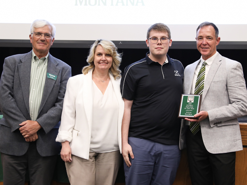 Dylan Baldwin receives the 2025 Student Employee of the Year award, standing with three adults at a ceremony.