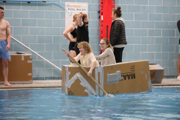 Students paddle a cardboard boat