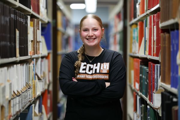 Tylar Clary poses for a photo in between library shelves