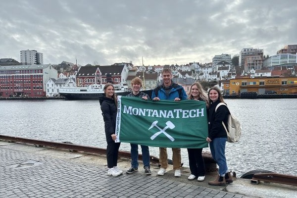 Montana Tech students pose with a Montana Tech flag in Stavanger port