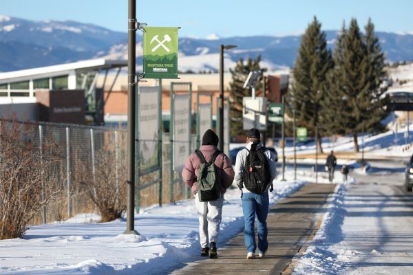 !Two students walk on campus