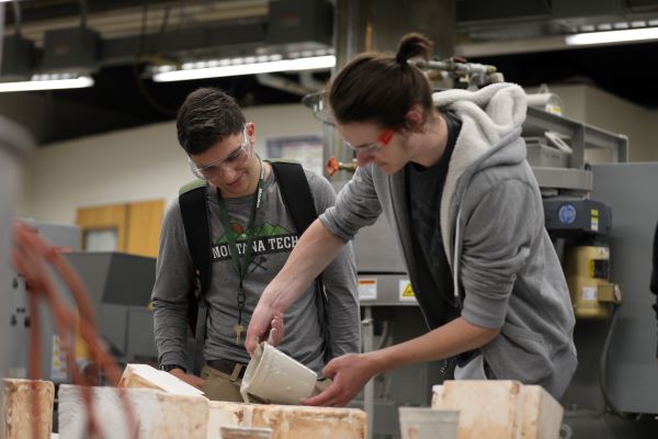 !Two students pour a gooey substance