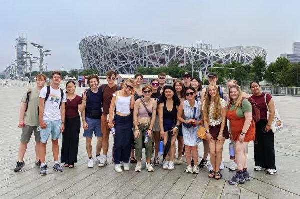 !Students stand in front of the National Stadium, also known as the Bird's Nest