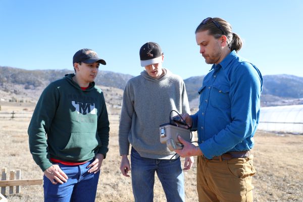 Three students conduct field research measuring radon