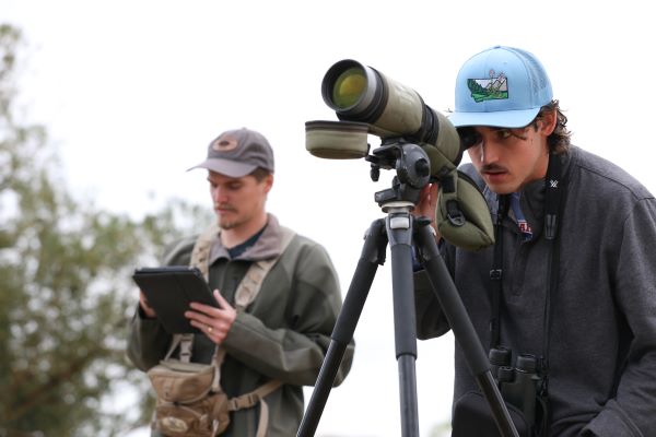 Caleb Lashway works with a clipboard while Ian Barville looks through a spotting scope